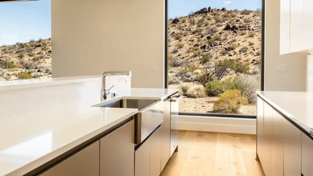 A bright kitchen with bare white counters and a polished sink, cleaned for a real estate listing